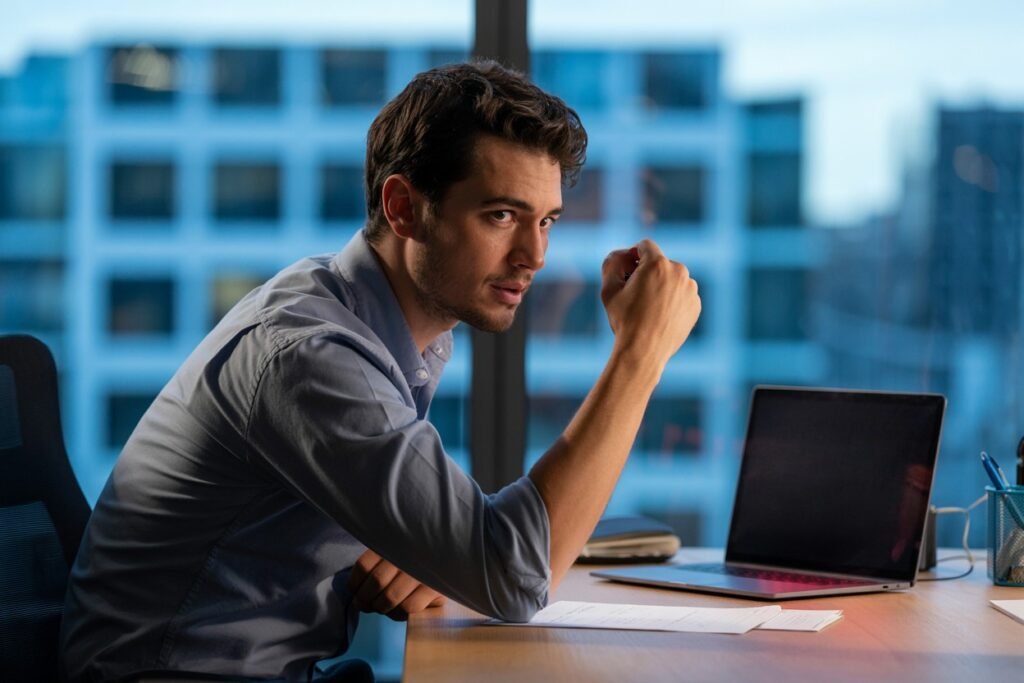 Concerned startup founder at a laptop, evaluating AI hiring tools and candidate applications in a modern office setting.